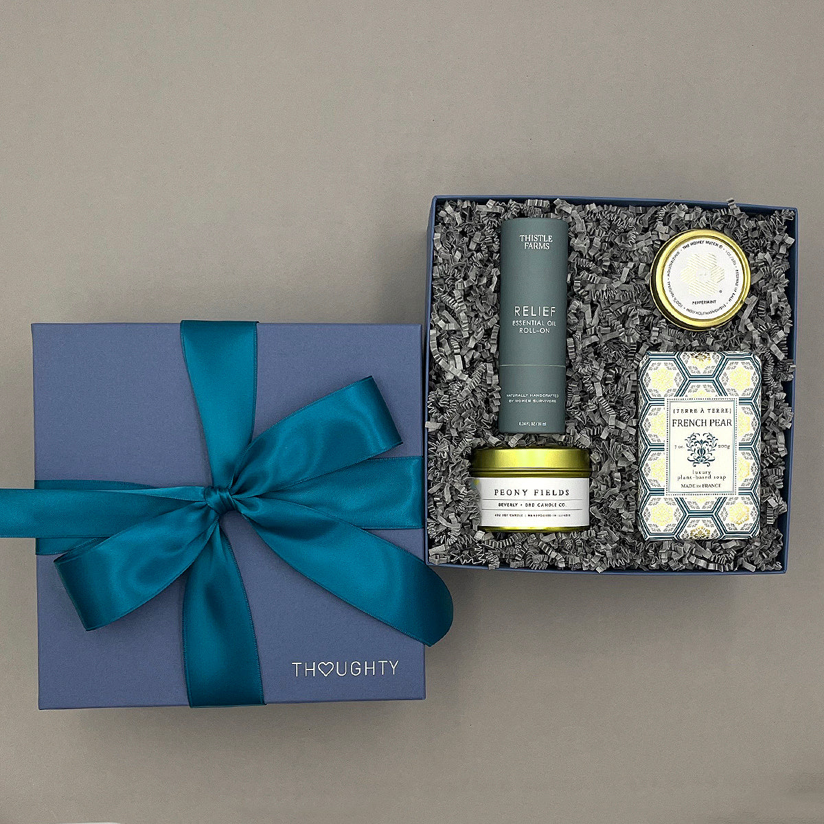 Gift set with a blue ribbon and products in a box on a gray background