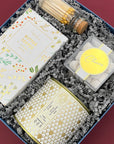 Winter White Gift Box featuring Candlefish candle, gold matches, and holiday snacks.