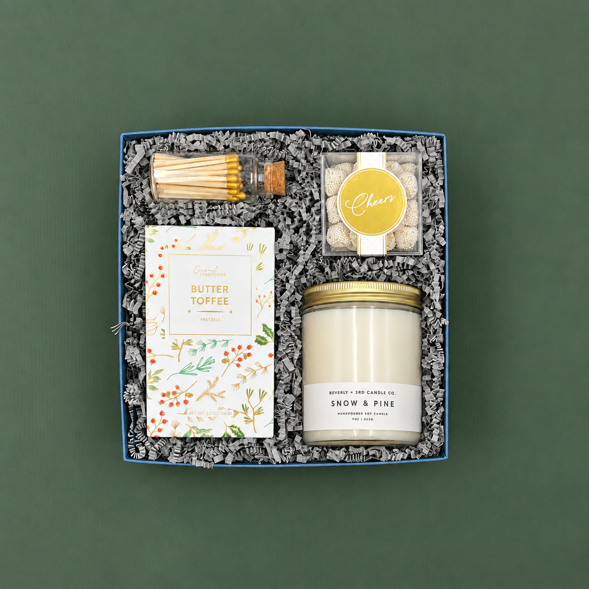 Winter White holiday gift box with Snow &amp; Pine candle, gold matches, butter toffee pretzels, and champagne gummies.